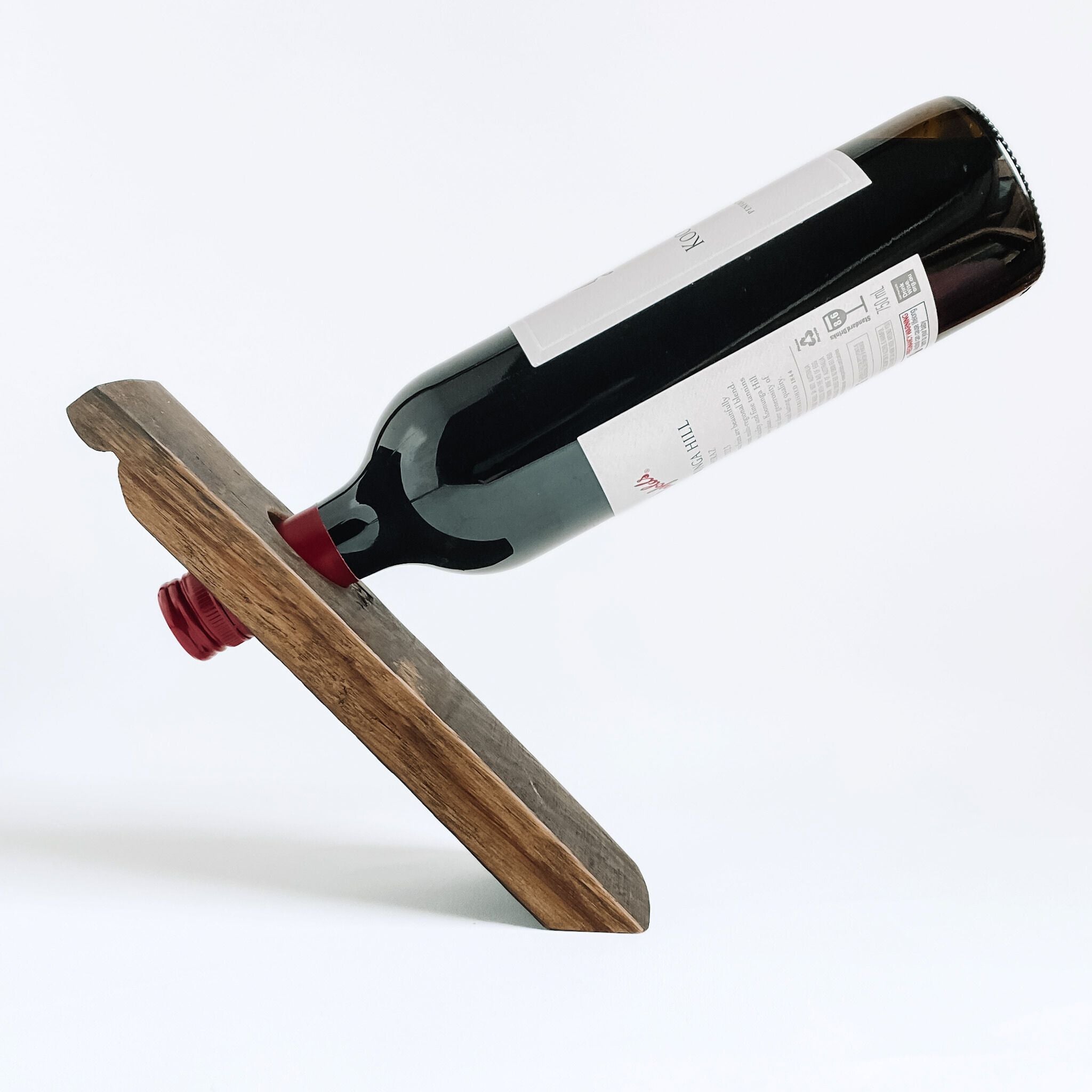 Barrel stave floating wine bottle holder with a red wine bottle on a white background, side view