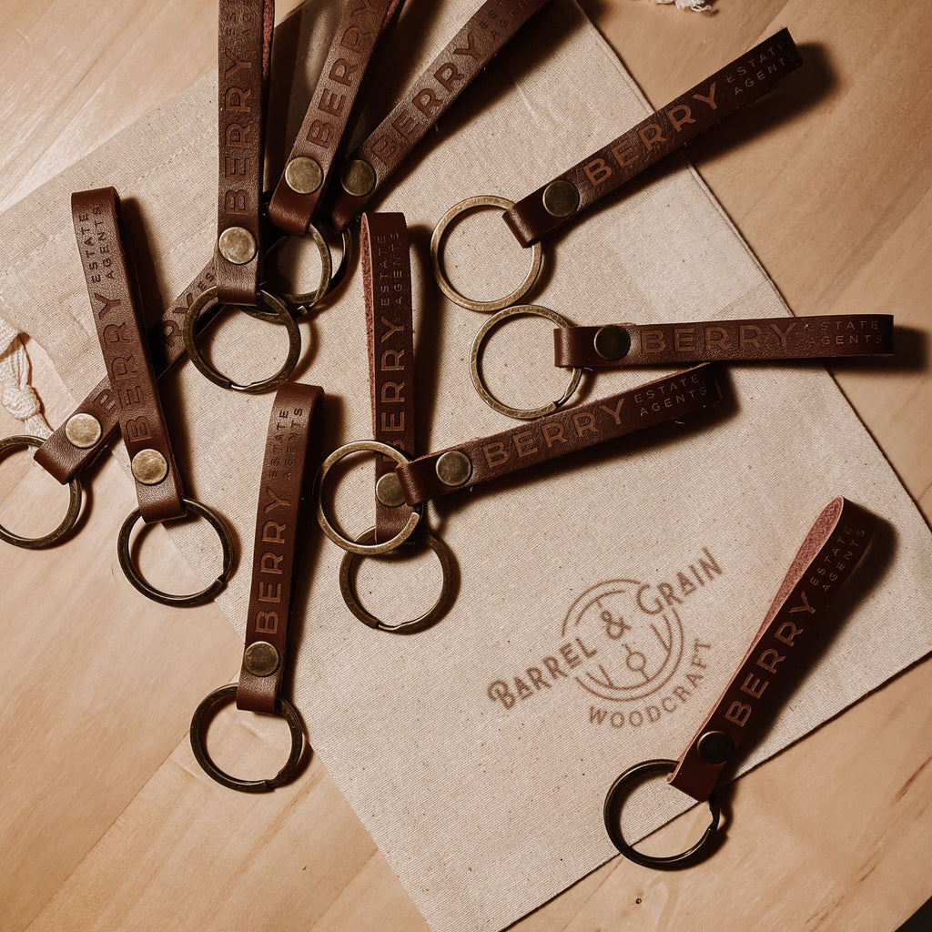 Bulk order of engraved leather keyrings arranged on a canvas bag
