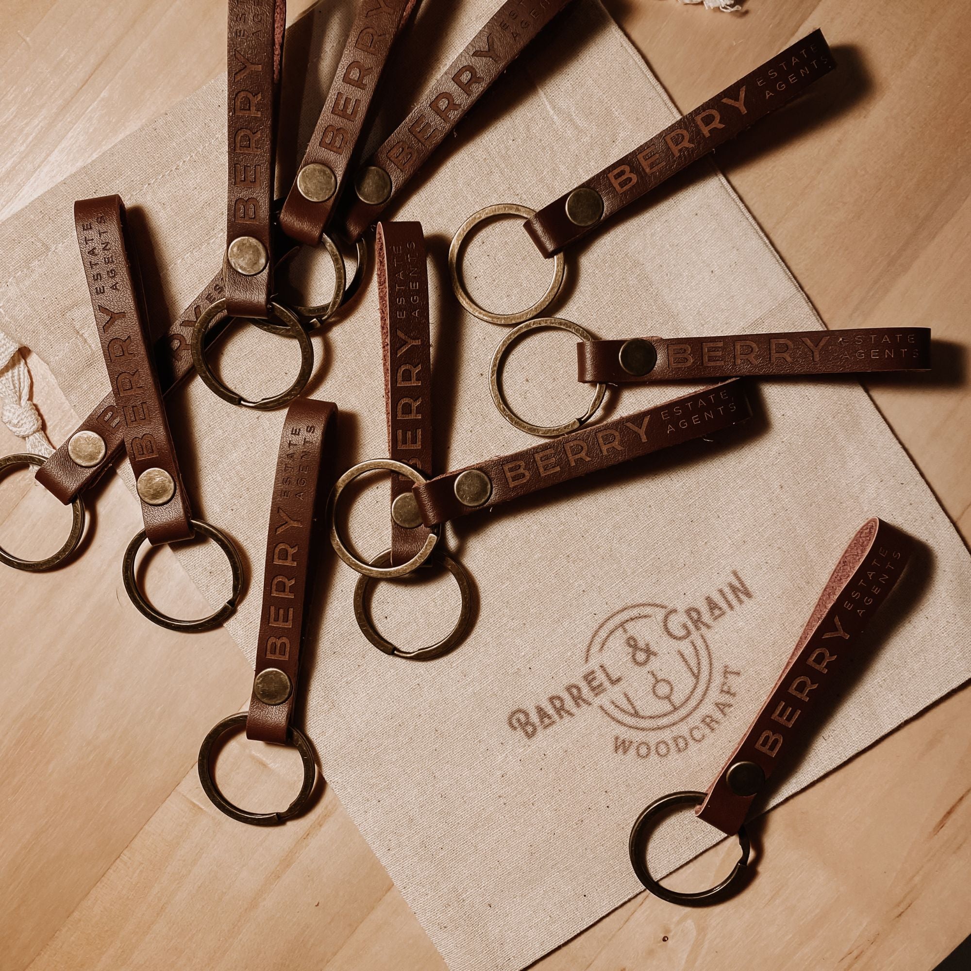 Bulk order of engraved leather keyrings arranged on a canvas bag