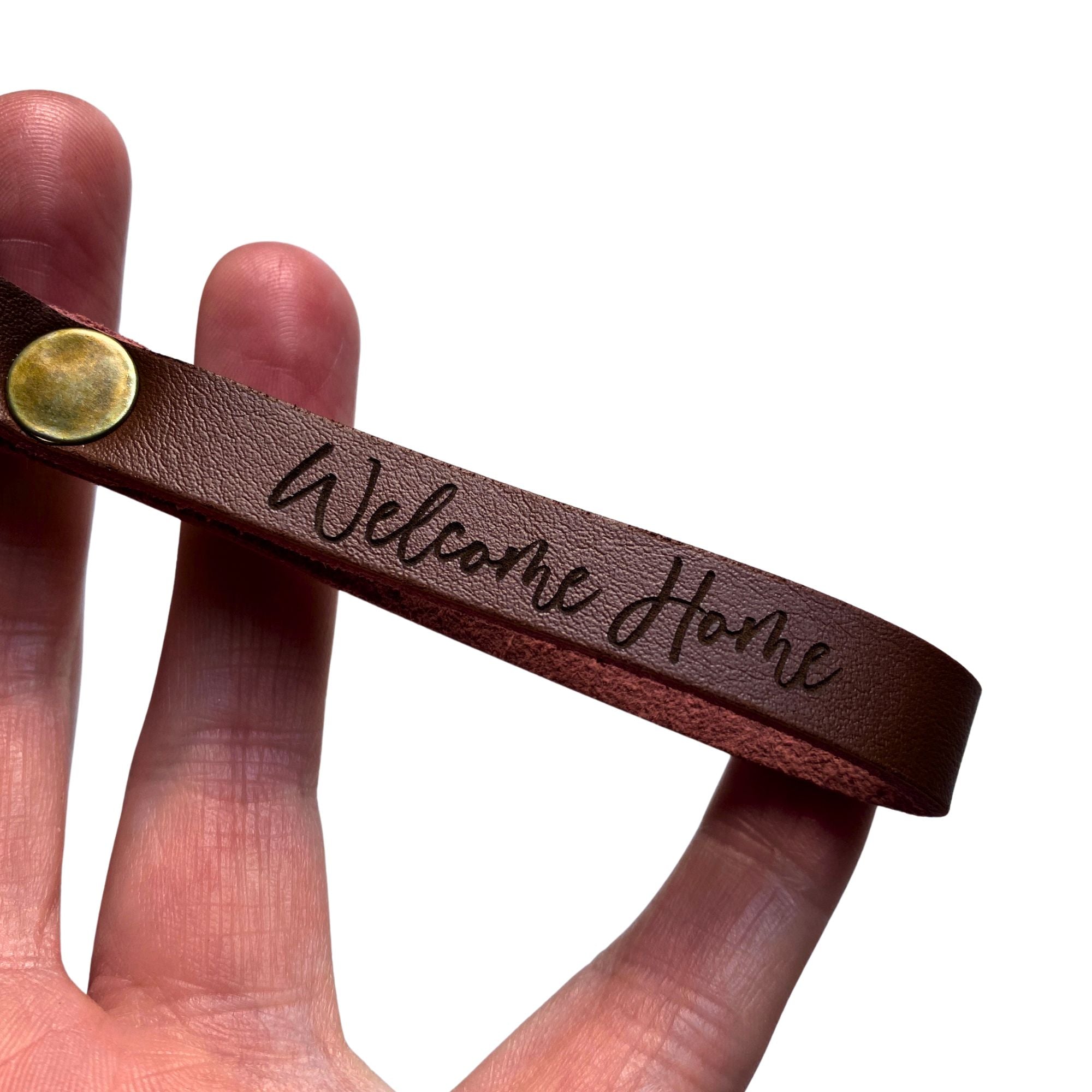 Hand holding a leather keyring engraved with 'Welcome Home' as a new-home settlement gift
