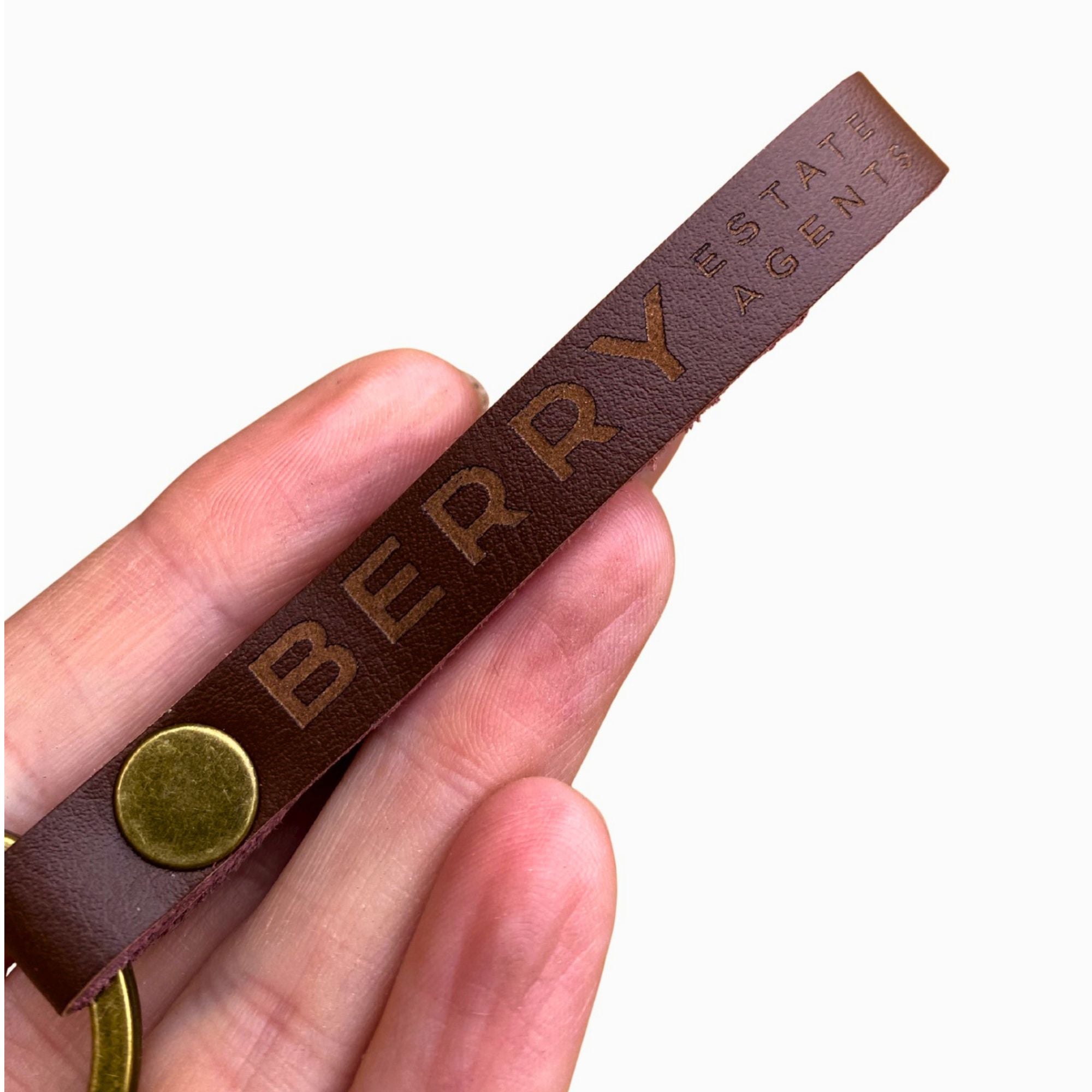 Hand holding a genuine leather keyring engraved with a corporate logo