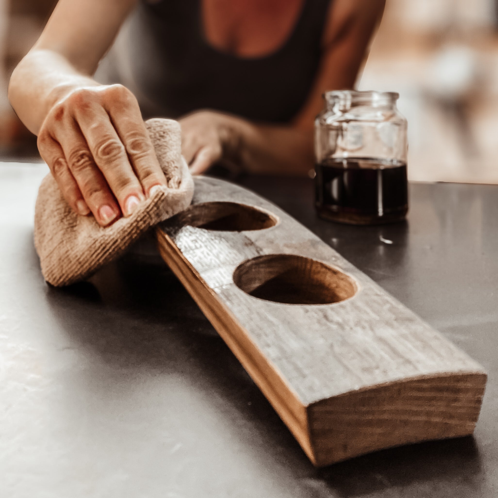 Hands oiling barrel stave flight board in workshop