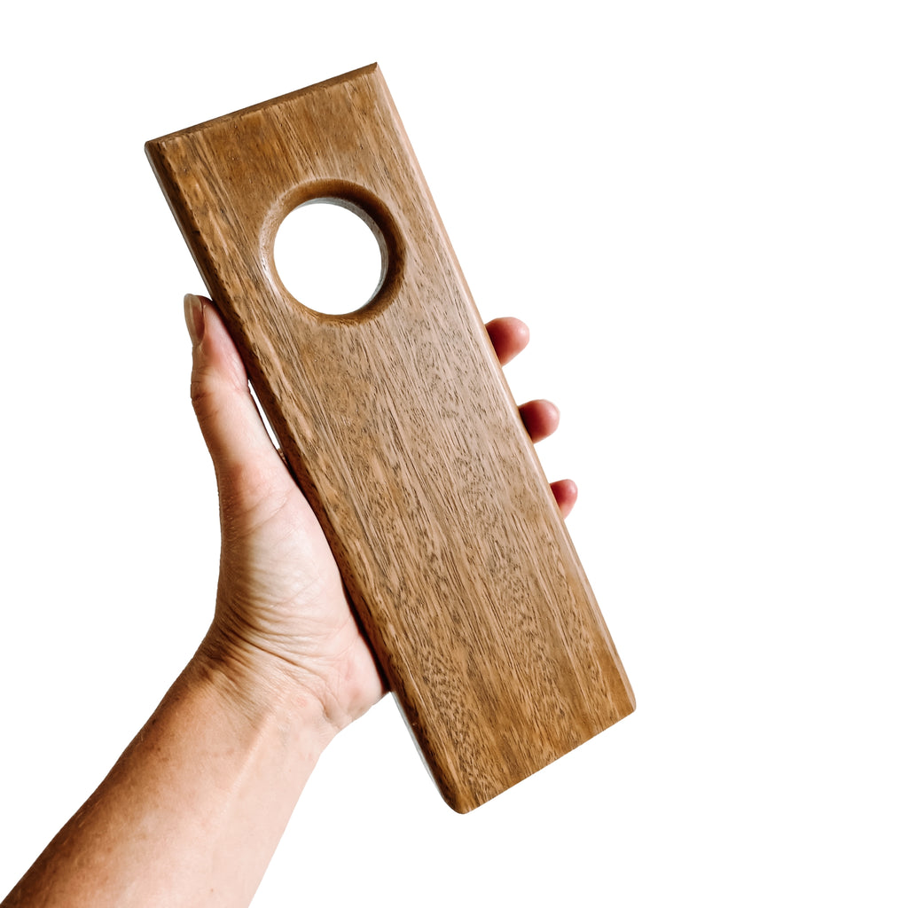 Hand holding a spotted gum wine holder on a white background