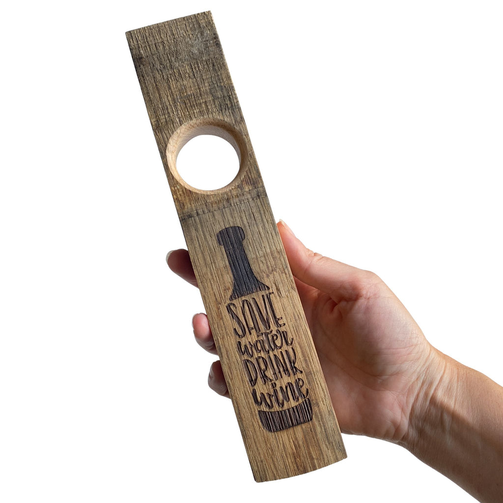 Hand holding engraved wine bottle holder - save water drink wine design.  Front view